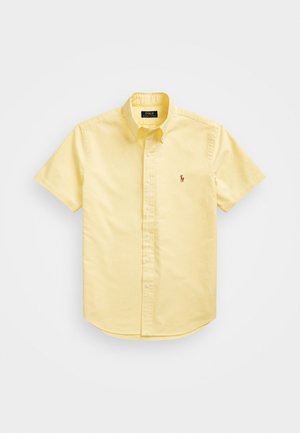 Chemise jaune clair à manches courtes, boutonnée, avec col et petit logo brodé sur la poitrine gauche.