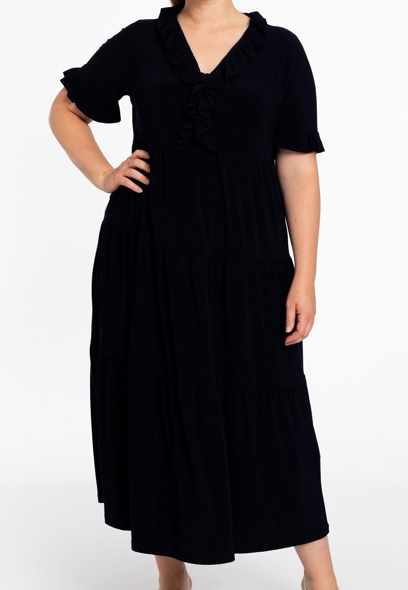 Robe bleu marine foncé avec un design à volants, comprenant un col à volants et des manches courtes. Tissu doux et coupe ample pour un porté confortable.