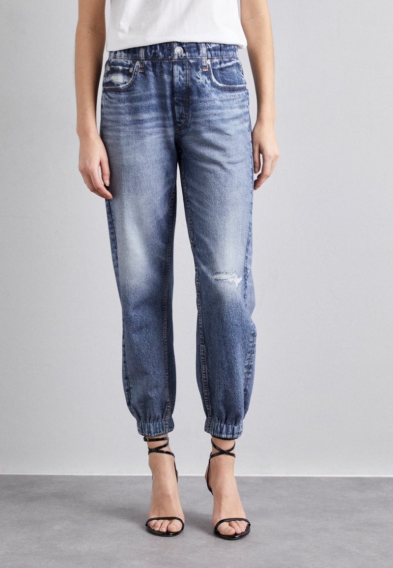 Lichtblauwe denim joggerbroeken met een elastische tailleband, opgestropen enkels en voorzakken. Kenmerkend voor een versleten kniedetail en een losse pasvorm.