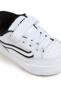 Sneaker bianco con tomaia in pelle testurizzata, dettagli neri, una cinghia con chiusura a strappo e lacci tradizionali, dotato di suola in gomma.