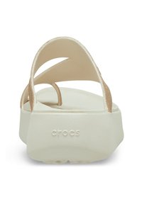Witte Crocs sandalen met een glanzende afwerking, voorzien van een roségouden glitterband en een dikke, gewatteerde zool, met reliëflogo op de achterkant.