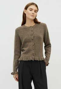 Barna kötött kardigán, amely lekerekített nyakkivágással, elülső gombokkal, valamint fodros aljjal és mandzsettákkal rendelkezik. Puha, texturált anyagból készült.