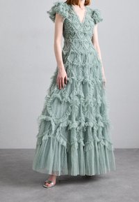 Robe vert clair avec un décolleté en V profond, des manches courtes à volants, des volants superposés et une texture à pois, dotée d'une jupe ample et d'une superposition transparente.