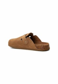 Sandal de ante marrón, tipo slip-on, con puntera redondeada, correa ajustable y suela texturizada similar al corcho. Presenta orificios de ventilación en los laterales.