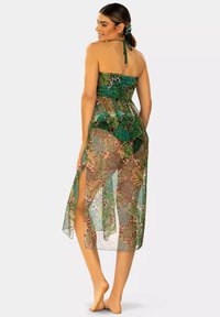 Zielona sukienka plażowa z tropikalnym wzorem, z dekoltem halter, przezroczystego materiału, z rozcięciami z przodu i dopasowanym biustem. Idealna na plażę.