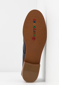 Semelle d'une chaussure marron avec motif cranté en zigzag et marquage coloré "everybody" au centre. Le talon présente de fines lignes horizontales antidérapantes.