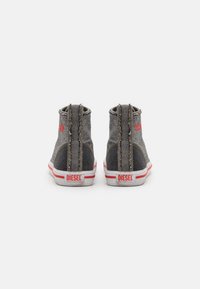 Šedé denimové vysoké tenisky s červenými akcenty, bílé gumové podrážky a viditelné švy na zadní a boční straně.