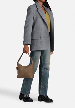 Šedý oversized blazer, žlutý top a oprané modré džíny. Hnědá kožená taška s krátkým popruhem. Černé boty na chunky podpatku.