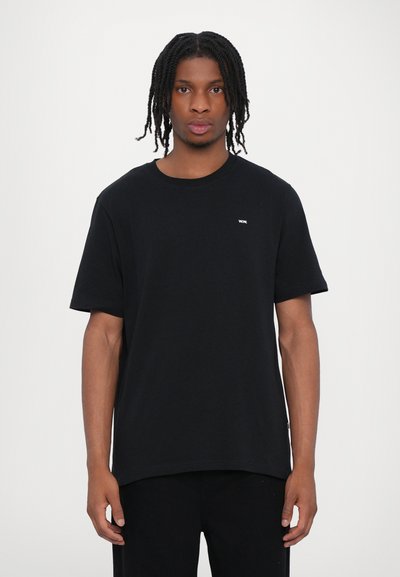 T-shirt en coton noir avec un col rond et des manches courtes. Présente un petit logo blanc sur la poitrine. Design simple avec une coupe droite.