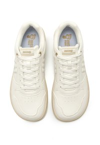 Zapatillas blancas de cuero con cordones, que presentan una superficie texturizada, detalles perforados en la puntera y una suela de goma beige. Marca dorada visible.