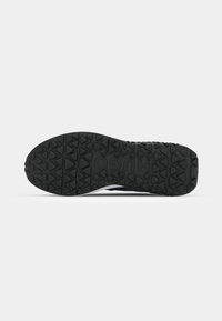 Semelle de chaussure en caoutchouc noir avec motif de bande de roulement triangulaire et le nom de la marque "HUGO" embossé au centre.
