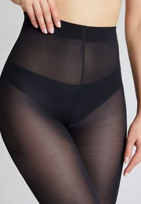 Collant neri trasparenti con un alto girovita. Realizzati in un materiale liscio e elasticizzato, presentano una finitura opaca e non mostrano pattern o accessori visibili.