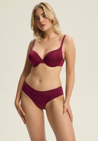 Fioletowy stanik bezszwowy i dopasowane figi, wykonane z gładkiego materiału. Stanik ma regulowane ramiączka i konturowany kształt dla lepszego wsparcia.