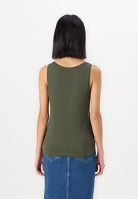 Olive green tank top made from soft fabric, featuring a round neckline and a fitted shape, paired with a denim skirt.