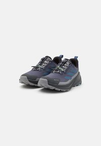 Scarpe da trail running di colore blu scuro e grigio con una tomaia texture, mesh traspirante e suola robusta. Presentano dettagli verdi e una punta rinforzata.