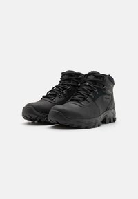 Bottes de randonnée noires avec un dessus en synthétique et en mesh, semelle extérieure robuste, embout renforcé et lacets réglables pour un ajustement sécurisé.