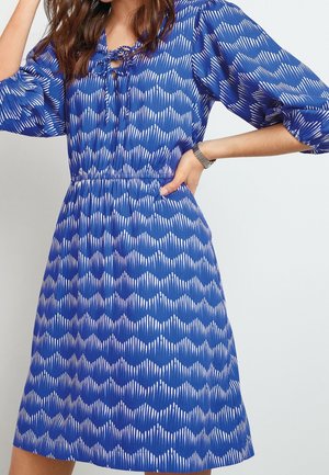 Abito blu con un motivo a onde in bianco, dalla vestibilità comoda, maniche 3/4 e vita arricciata. Include un collo con lacci.
