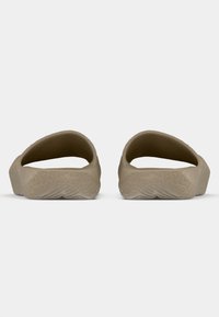 Μπεζ ελαστικά παντόφλες με ανοιχτή πλάτη, καμπύλες άκρες και υφή σόλας που διαθέτει μοτίβα φύλλων. Ελαφρύς και ευέλικτος σχεδιασμός.