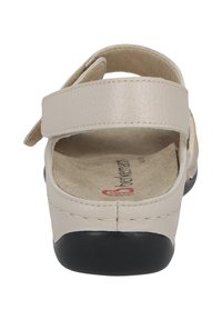 Light beige leather sandal with a wide strap, adjustable velcro closure, and a black rubber sole. Features a soft, textured footbed.