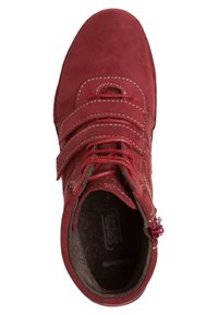 Bottine en cuir rouge montant jusqu'à la cheville, dotée de deux sangles Velcro, d'une couture contrastante et d'une doublure intérieure texturée. Comprend un détail de fermeture éclair sur le côté.