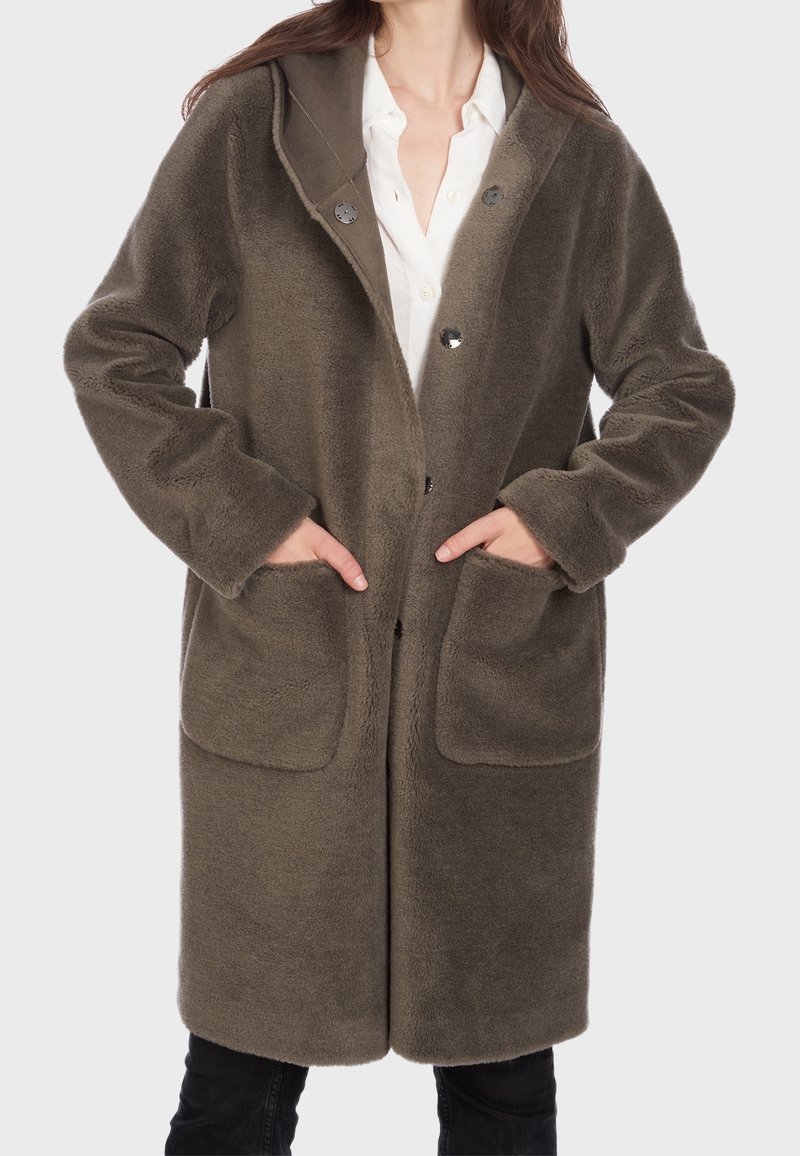Cappotto in pile verde oliva lungo con cappuccio, dotato di due tasche frontali e chiusure a bottone. Tessuto morbido e vestibilità comoda.
