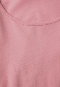 Vaaleanpunainen kangas, jossa on sileä pinta, pyöreä pääntie ja kontrastiväriset ompeleet. Sopii vapaa-aikaan.