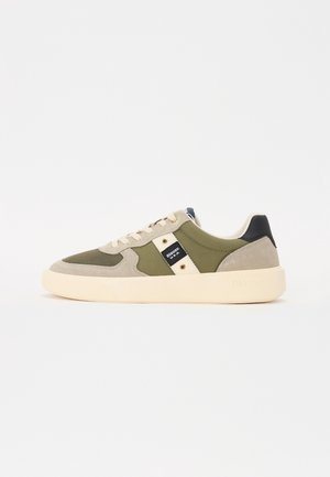 Lage sneaker met olijfgroene stof, beige suède overlays, crèmekleurige zool, witte veters, zwart hielstuk en merkembleem aan de zijkant.