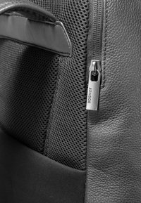 Sort lædertaske med mesh-paneler, der har en fremtrædende lynlåslukning og metal-lynlåsetag mærket "Bognor." Teksturerede detaljer overalt.