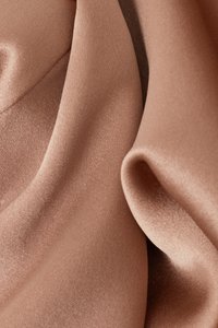 Tela suave de color rosa polvoriento con una textura suave y satinada; presenta pliegues fluidos y un brillo sutil, creando capas drapeadas y delicadas.