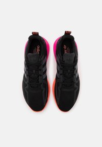 Svarta sportskor med en texturerad ovandel, prydda med tre mörkgrå ränder, en rosa häl och livfulla orange sulor.