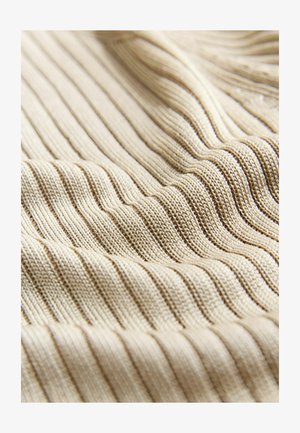 Beige ribbad stickad tyg med växlande texturerade ränder, som visar en mjuk och slät yta.
