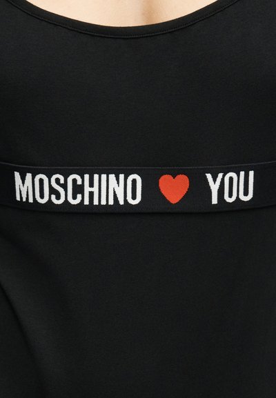 Μαύρο ένδυμα με οριζόντια λωρίδα με την επιγραφή "MOSCHINO" σε λευκό κείμενο, κόκκινο σύμβολο καρδιάς και το "YOU" σε λευκό κείμενο στην περιοχή του στήθους.