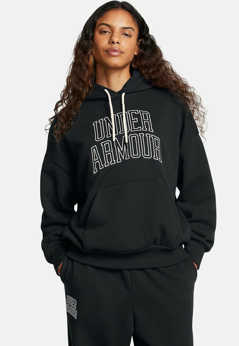 Juoda su kapuze palaidinė su baltais užrašais "UNDER ARMOUR", turinti priekinę kišenę ir pylimos briaunomis. Su derančiomis juodomis sportinėmis kelnėmis.