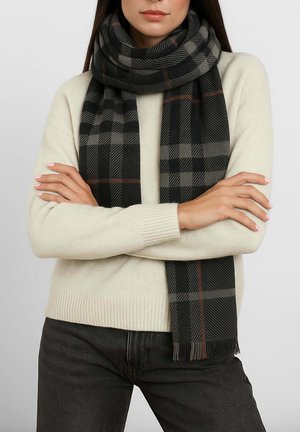 Sciarpa a quadri nera e grigia realizzata in tessuto morbido, con estremità a frange e una linea accentuata arancione, avvolta attorno a un maglione neutro.