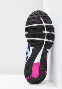 Baskets de sport avec une semelle en caoutchouc noire, motif texturé, semelle intermédiaire blanche et accents violets ; conçues pour l'adhérence et le confort.