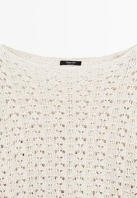 Strickpullover in Off-White mit luftiger Gestaltung und weiter Ausschnitt. Etikett lautet "Massimo Dutti, hergestellt in China." Mit einem zarten Muster strukturiert.