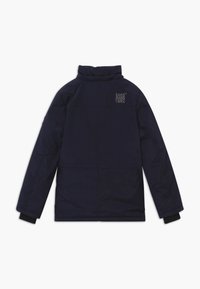 Donkerblauwe gewatteerde jas met hoge kraag, elastische manchetten en doorgestikte panelen. Heeft zilverkleurige opdruk "CARS JEANS 1982" op de achterkant.