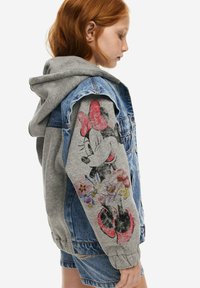 Džínová bunda s šedou mikinou, na rukávu s potiskem Minnie Mouse a květinami. Kombinace materiálů, barevné akcenty.