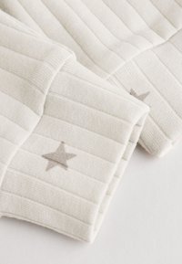 Soft white ribbed fabric with light gray star patterns on folded cuffs, shown close-up on a white background.