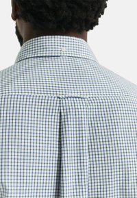 Hemd mit Knopfleiste in kariertem Muster in Blau und Weiß. Verfügt über einen klassischen Kragen und eine Rückenfalte für Passform und Bewegungsfreiheit.