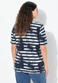 Camiseta a rayas en azul marino y blanco, hecha de una tela suave, con un corte relajado, mangas cortas y una vista trasera que muestra un patrón texturizado.