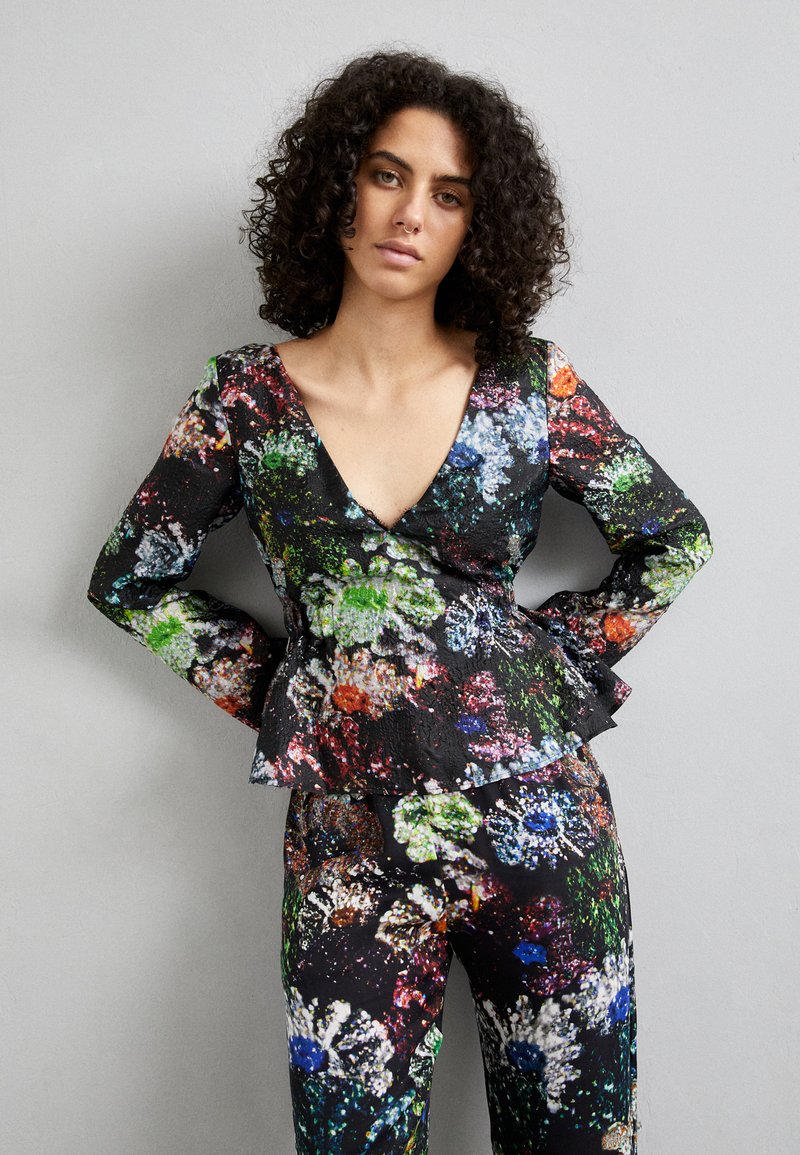 Haut en tissu noir à motifs floraux avec un décolleté en V profond et un ourlet peplum ; associé à un pantalon floral assorti. Présente des motifs de fleurs abstraites colorées.