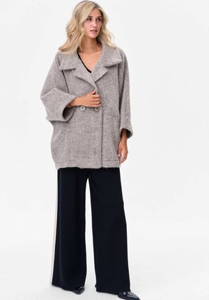 Manteau en mélange de laine gris surdimensionné avec un devant à double bouton, un grand col et des manches larges ; associé à un pantalon noir à jambes larges.