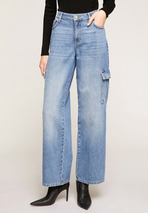 Lichtblauwe jeans met wijde pijpen van denim, met een voorzak, een zijcargo-zak en subtiele vervaging, gecombineerd met puntige zwarte hakken.