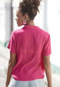 Korte mouwen, roze, linnen overhemd met een kraag en een relaxte pasvorm. Beschikt over een licht doorschijnende textuur en is gecombineerd met lichtblauwe denim jeans.