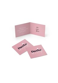 Rozā apsveikumu kartīšu komplekts, kas sastāv no salocītas kartītes ar rokraksta stila ziņojumu un divām plakano kartītēm, no kurām viena ir ar melnu skriptu uzrakstīta vārds "Danke".