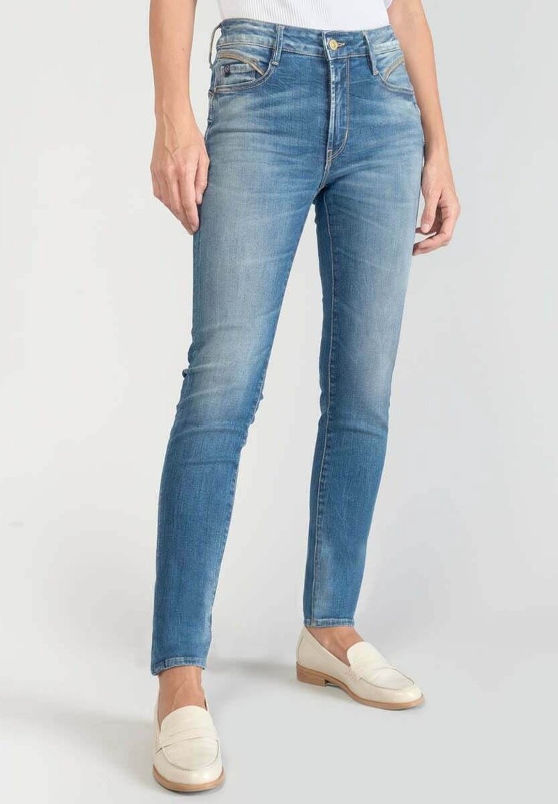 Jeans skinny blu in denim sbiadito con vita medio-alta e design classico a cinque tasche. Abbinati a mocassini di colore chiaro.