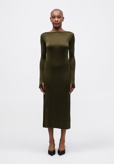 Robe olive verte à manches longues en tissu lisse et extensible, avec un décolleté bateau et une silhouette ajustée, se terminant sous le genou.