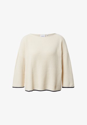 Kremowy dzianinowy sweter o luźnym kroju, szerokim dekolcie i rękawach do połowy przedramienia. Z kontrastującymi czarnymi wykończeniami na dole i na rękawach.