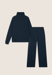 Completo da casa di colore blu navy composto da un pullover con collo alto e pantaloni coordinati. Tessuto morbido, vestibilità comoda e maniche lunghe con polsini.